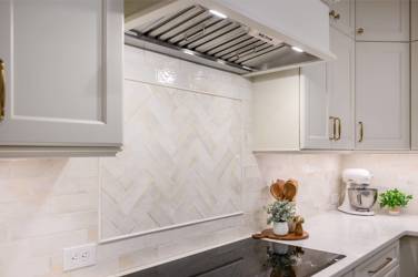 White kitchen with gray island and herringbone tile backsplash in Cary, NC