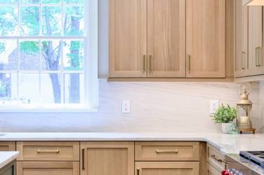White oak kitchen with sage green island and white quartzite waterfall counters in Raleigh, NC